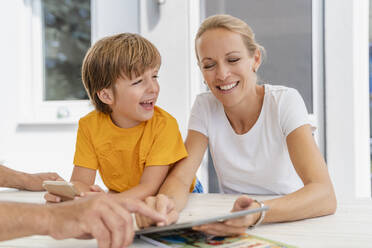 Happy mother and son doing homework and using tablet together on terrace - DIGF08183