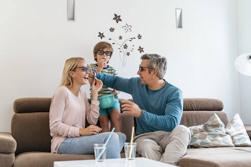 Vater, Mutter und Sohn mit 3d-Brille auf der Couch zu Hause - DIGF08206
