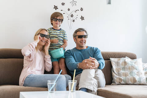Vater, Mutter und Sohn mit 3d-Brille auf der Couch zu Hause beim Fernsehen, lizenzfreies Stockfoto