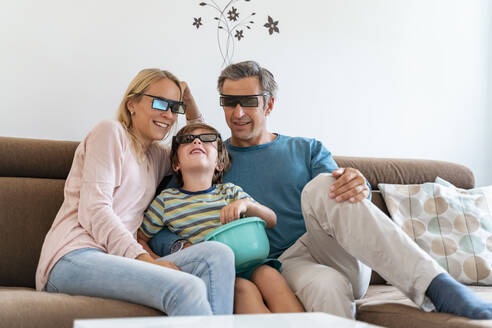 Vater, Mutter und Sohn mit 3d-Brille auf der Couch zu Hause beim Fernsehen - DIGF08208