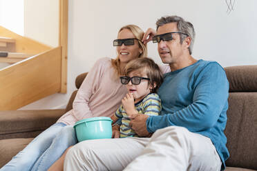 Vater, Mutter und Sohn mit 3d-Brille auf der Couch zu Hause beim Fernsehen - DIGF08210