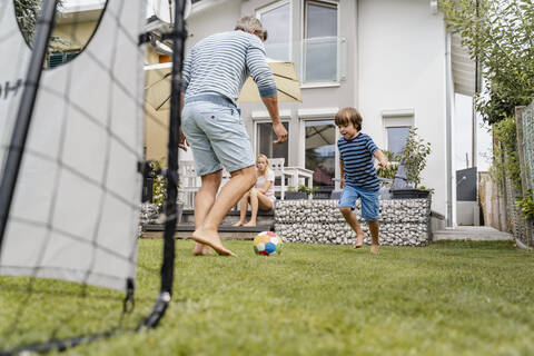 Vater und Sohn spielen Fußball im Garten, lizenzfreies Stockfoto