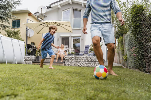 Father and son playing football in garden - DIGF08240