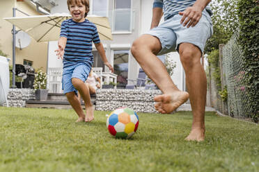 Father and son playing football in garden - DIGF08241