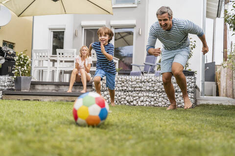 Vater und Sohn spielen Fußball im Garten, lizenzfreies Stockfoto