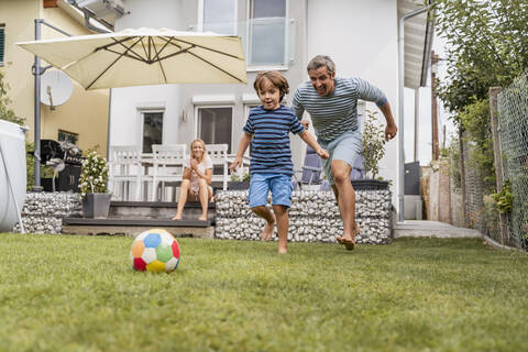 Vater und Sohn spielen Fußball im Garten, lizenzfreies Stockfoto