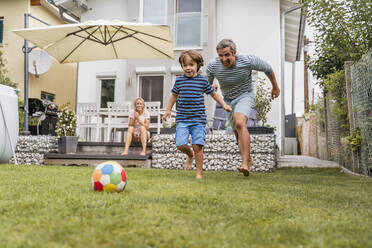 Vater und Sohn spielen Fußball im Garten - DIGF08243