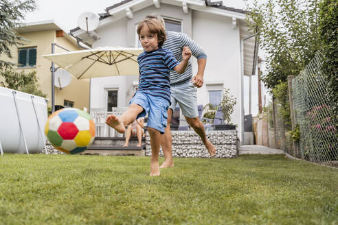 Vater und Sohn spielen Fußball im Garten - DIGF08244