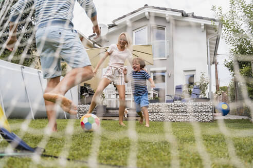 Glückliche Familie spielt Fußball im Garten - DIGF08251