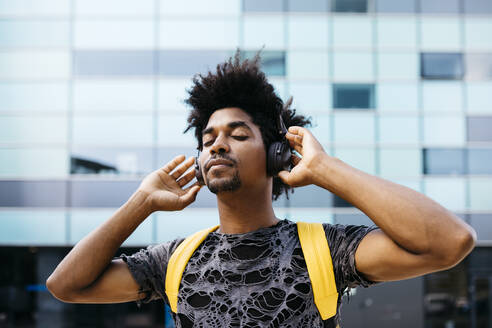 Portrait of man listening music with cordless headphones, Barcelona, Spain - JRFF03703