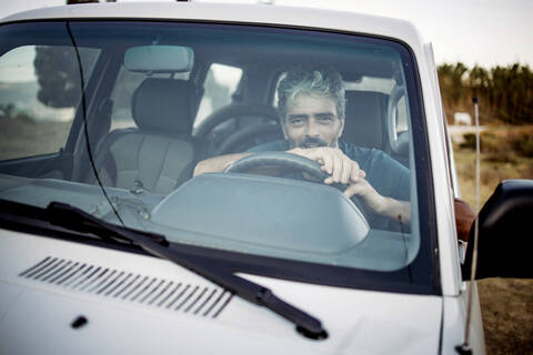 Lächelnder reifer Mann, der in seinem Geländewagen sitzt, lizenzfreies Stockfoto
