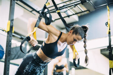 Young woman doing suspension traning in the gym - OCMF00666