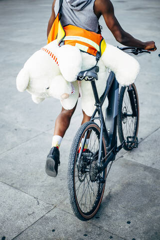 Fahrradkurier liefert einen Teddybär aus, lizenzfreies Stockfoto