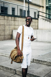 Young man with earphones and mobile phone in the city - OCMF00679