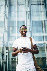 Happy young man with mobile phone in the city - OCMF00684
