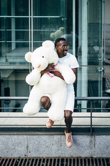 Lächelnder junger Mann hält riesigen Teddybär - OCMF00687