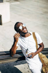 Happy young man with earphones and mobile phone in the city - OCMF00690