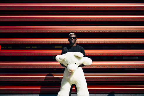 Portrait of cool young man holding huge teddy bear - OCMF00697