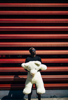 Portrait of cool young man holding huge teddy bear - OCMF00698
