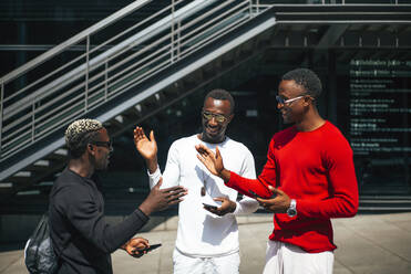 Drei coole junge Männer mit Handys treffen sich in der Stadt - OCMF00703
