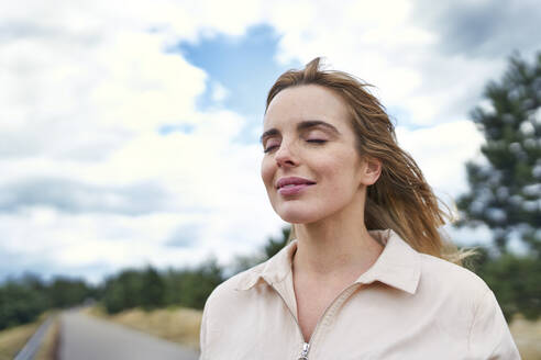 Portrait of smiling woman with closed eyes in nature - BSZF01422