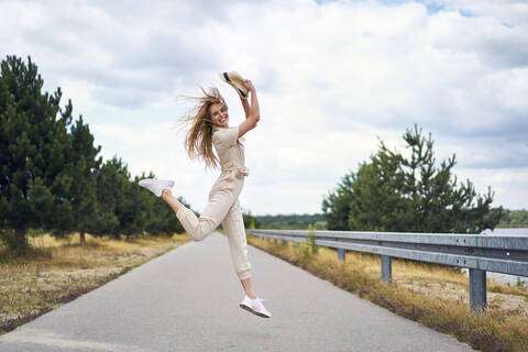 Fröhliche Frau springt auf Landstraße, lizenzfreies Stockfoto