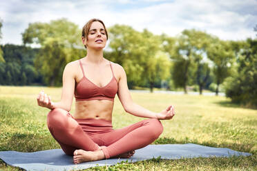 Frau übt Yoga im Park und meditiert - BSZF01455