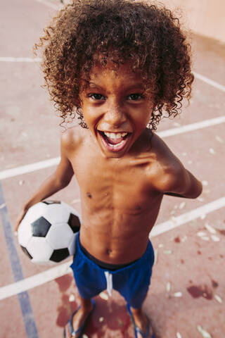 Porträt eines Jungen, der einen Fußball auf einem Fußballfeld hält, lizenzfreies Stockfoto