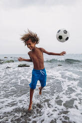 Boy playing with a football on the beach - LJF00987