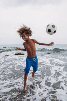 Junge spielt mit einem Fußball am Strand - LJF00987