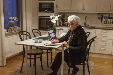Ältere Frau benutzt Laptop in der Küche - FOLF10812