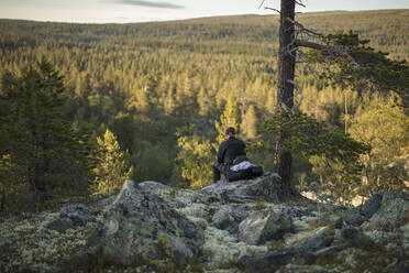 Mann sitzt auf einem Felsen im Naturreservat Tofsingdalen in Schweden - FOLF10858