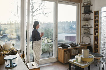 Woman by window in pottery workshop - FOLF10892