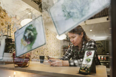 Frau benutzt Smartphone in einem Cafe - FOLF10915