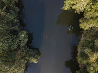 Drohnenaufnahme eines Bootes auf einem Fluss inmitten von Bäumen auf Bali, Indonesien - KNTF03354