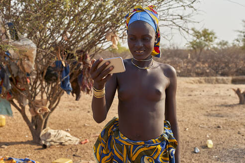 Junge Mucubal-Frau überprüft ihr Smartphone, Tchitundo Hulo, Virei, Angola - VEGF00603