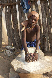 Mädchen vom Stamm der Mucubal mahlt Mais auf traditionelle Weise, Tchitundo Hulo, Virei, Angola - VEGF00605