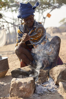 Alte Mucubal-Frau beim Kochen auf traditionelle Weise, Tchitundo Hulo, Virei, Angola - VEGF00608