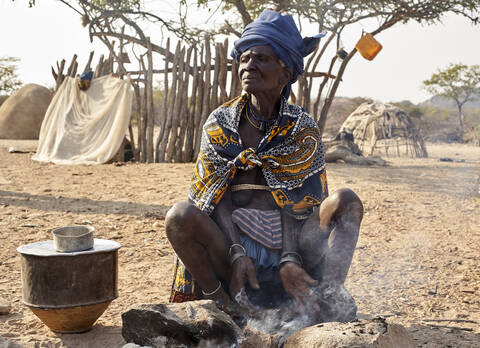 Alte Mucubal-Frau beim Kochen auf traditionelle Weise, Tchitundo Hulo, Virei, Angola, lizenzfreies Stockfoto