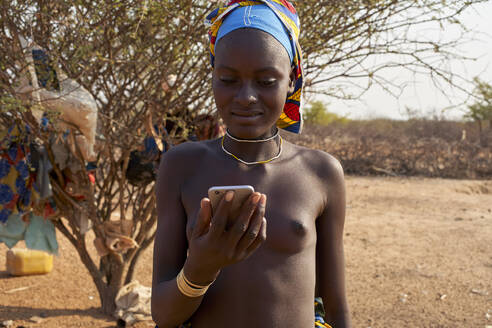 Junge Mucubal-Frau überprüft ihr Telefon, Tchitundo Hulo, Virei, Angola - VEGF00610