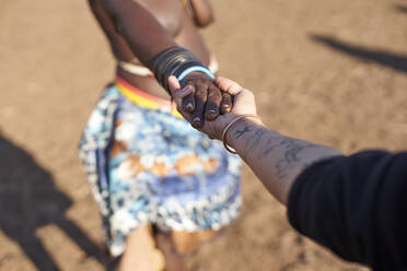 Muhacaona traditional woman and white woman holding hands, Oncocua, Angola - VEGF00640