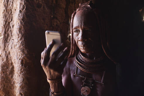 Alte Himba-Frau überprüft ihr Smartphone, Oncocua, Angola - VEGF00645