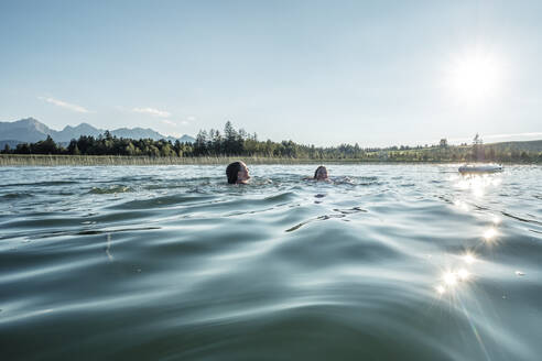 Zwei Mädchen schwimmen in einem See bei Sonnenschein, Bannwaldsee, Allgäu, Bayern, Deutschland - WFF00088