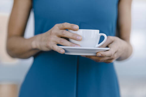 Businesswoman holding cup of coffee, mid section - KNSF06312