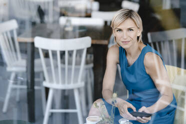 Geschäftsfrau, die in einem Café sitzt und ein digitales Tablet benutzt - KNSF06314