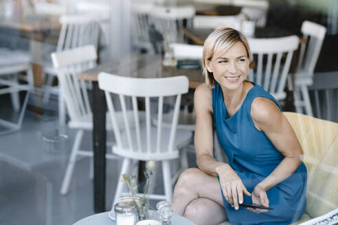 Businesswoman sitting in coffee shop, using digital tablet - KNSF06315