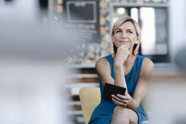 Businesswoman sitting in coffee shop, using digital tablet - KNSF06316