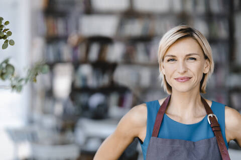 Porträt einer blonden Frau, die vor ihrem eigenen Café steht, lizenzfreies Stockfoto