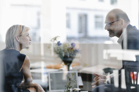 Businessman and woman having a meeting in a coffee shop, discussing work stock photo