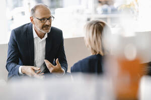 Businessman and woman having a meeting in a coffee shop, discussing work - KNSF06328